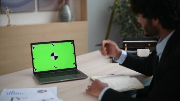 Sur les gars vue épaule d'un ordinateur portable avec un écran vert chromatique. Succès gars indien est d'avoir un webinaire en ligne, écouter une conférence, acquérir des connaissances, prendre des notes dans un carnet - Séquence, vidéo