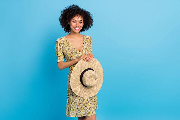 Portrait of positive friendly girl hold sunhat beaming smile look camera isolated on blue color background. - 写真・画像