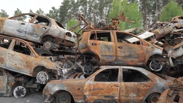 A lot of shot and destroyed civilian cars at the car cemetery in Irpin, Ukraine. Russian military aggression in Ukraine in 2022 - Materiał filmowy, wideo