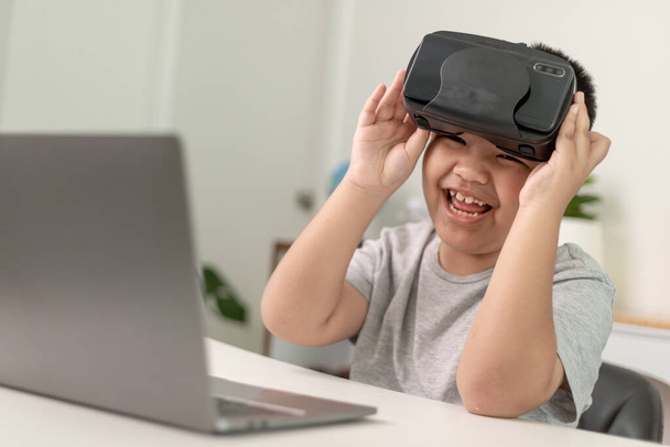 Asiático pequeño niño con gafas VR estudiar ciencias en casa, curioso estudiante lleva un auricular de realidad virtual para estudiar ciencias en casa estudio en línea futurista estilo de vida aprendizaje - Foto, Imagen