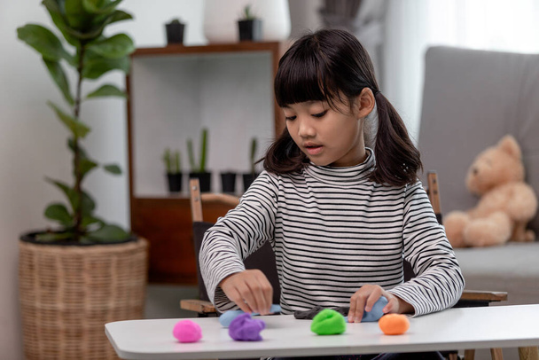 The little girl is learning to use colorful play dough in a well lit room  - Photo, Image