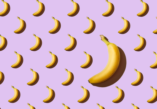 Texture of bananas on a purple background, one large banana, a pattern of bananas - Foto, Imagem
