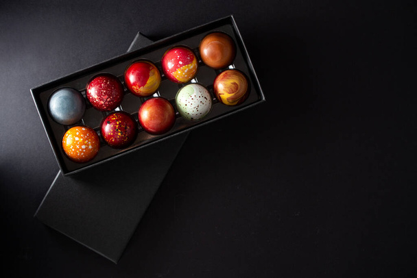 Open gift box with assortment of homemade chocolate bonbons. Modern hand painted chocolate candy. Product concept for chocolatier - 写真・画像
