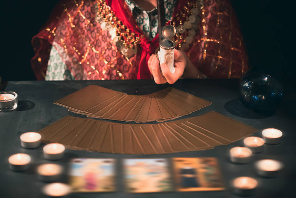 Fortune teller with tarot cards on table near burning candles.Tarot cards spread on table with crystal ball.Forecasting concept. - Zdjęcie, obraz