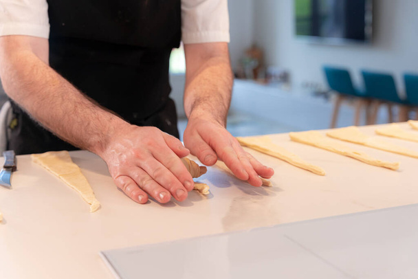 Detalle de las manos de un hombre cocinando croissants, moldeando con la hojaldre, trabajo en casa - Foto, imagen