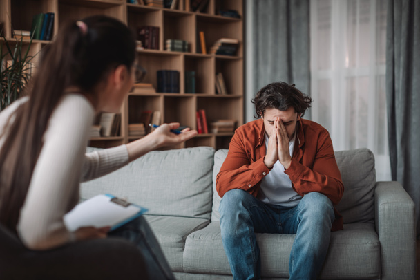 Europäische millennial Frau Arzt Psychologe beruhigen weinende unglückliche männliche Klient in Klinik Büro Interieur. Medizinische Unterstützung und Beratung, Gesundheitsfürsorge, Behandlung von Depressionen und psychischen Problemen - Foto, Bild