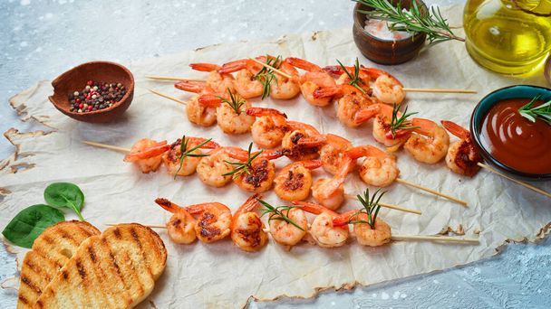 Shrimp for barbecue. Grilled shrimps on skewers with lemon and garlic. Seafood. On a stone background. - Photo, image