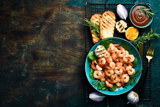 A plate of grilled shrimp with herbs, garlic and lemon. On a dark stone background. Top view. - Zdjęcie, obraz
