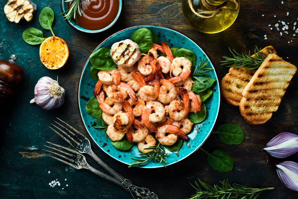 A plate of grilled shrimp with herbs, garlic and lemon. On a dark stone background. Top view. - Фото, изображение