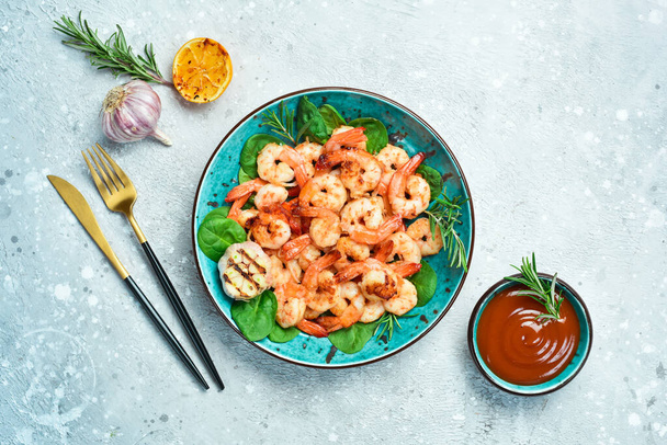 Grilled shrimp served with lemon and sauce. Seafood on a plate. On a gray stone background. Top view. - Foto, Bild