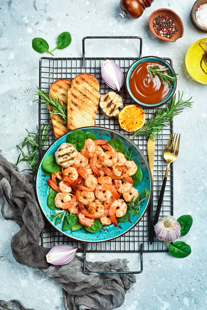 Grilled shrimp served with lemon and sauce. Seafood on a plate. On a gray stone background. Top view. - Foto, Imagem