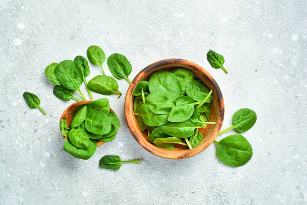 Green spinach leaves on a gray stone background. Healthy food. Top view. - Foto, afbeelding