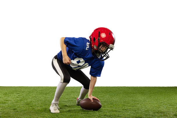 In motion. Athletic kid, beginner american football player in sports uniform and helmet training isolated on white background. Concept of sport, challenges, action, achievements. - Foto, afbeelding