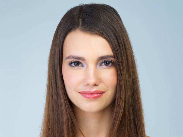 Studioporträt einer schönen jungen Frau, die vor blauem Hintergrund posiert - Foto, Bild