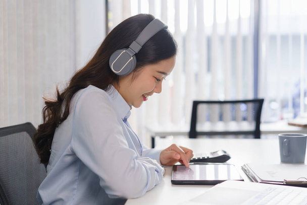 Obchodní koncepce, Podnikatelka ve sluchátkách poslouchat hudbu a kontrolu finanční zprávy na tabletu. - Fotografie, Obrázek