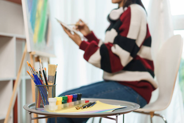 Концепция искусства, азиатская художница использует кисть для погружения в цветовую палитру для рисования на холсте. - Фото, изображение
