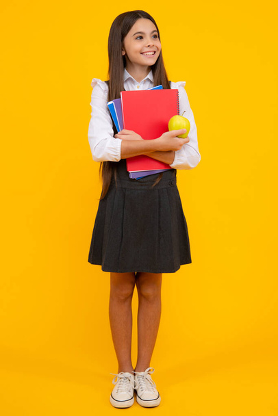 Back to school. Full length of teenager school girl with backpack hold aplle ready to learn. School children with school bag on isolated yellow studio background - Photo, Image