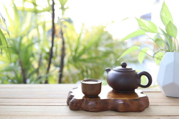 Посуда чайник и чашка с деревянным подносом на деревянном столе - Фото, изображение