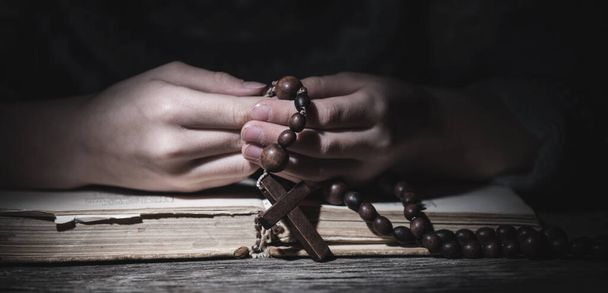 Prière à Dieu. La jeune fille prie avec le chapelet et lit la Bible. Image horizontale. Concentration sélective. - Photo, image