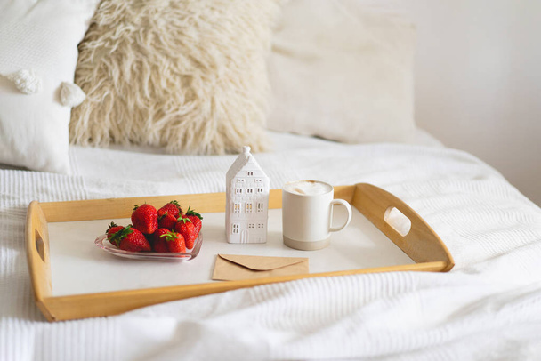 Still life details in home interior of living room. Tray, cup coffee, strawberries and card on a bed. Cozy home - Фото, изображение