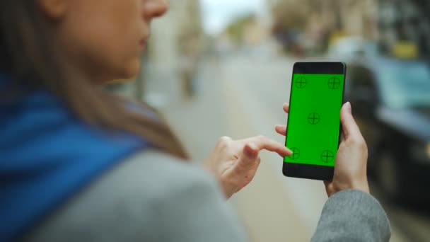 Kobieta na ulicy za pomocą smartfona z zielonym ekranem makiety w trybie pionowym. Dziewczyna przeglądająca Internet, oglądająca treści, filmy, blogi. - Materiał filmowy, wideo