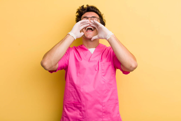 young handsome guy feeling happy,giving a big shout out with hands next to mouth. nurse concept - 写真・画像