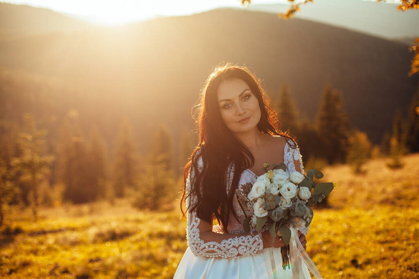 Happy beautiful young bride outside on a summer meadow at the sunset - Foto, Imagen