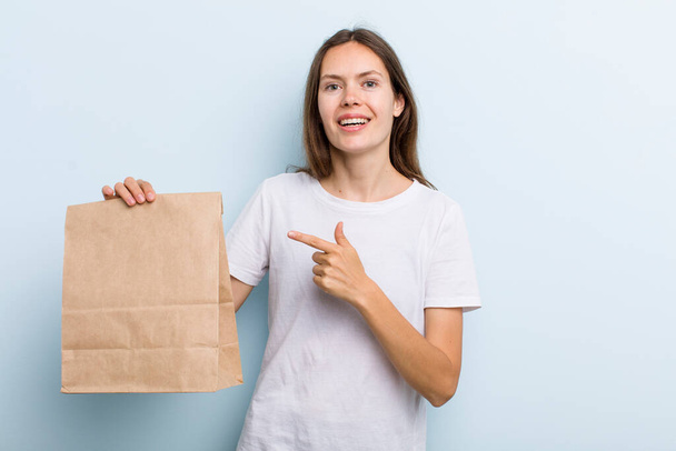 young adult woman looking excited and surprised pointing to the side. delivery and take away concept - Foto, afbeelding