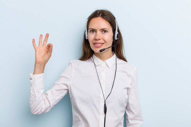 young adult woman feeling happy, showing approval with okay gesture. telemarketer concept - Foto, Imagen