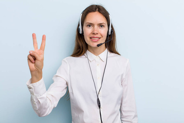 young adult woman smiling and looking friendly, showing number two. telemarketer concept - Photo, image