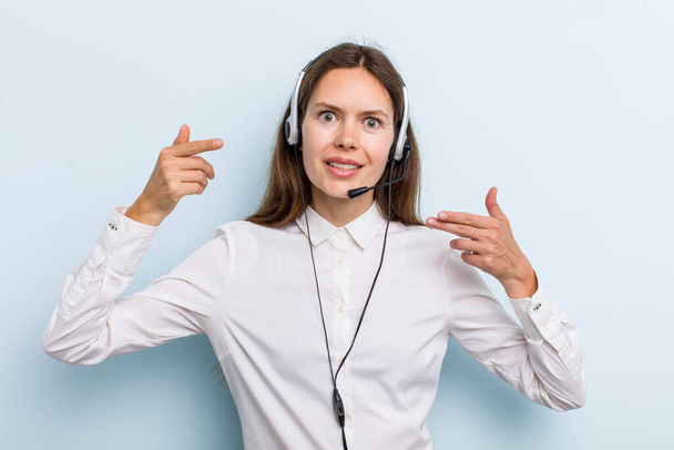 young adult woman smiling confidently pointing to own broad smile. telemarketer concept - Photo, image
