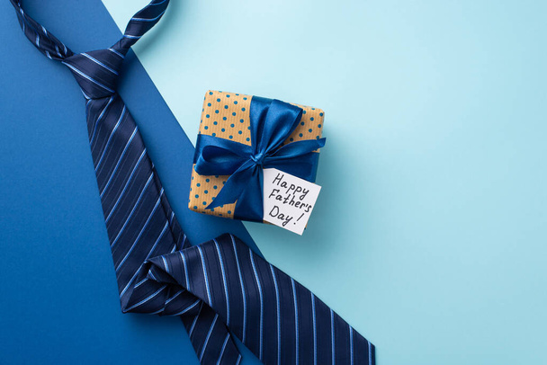 Apák napja koncepció. Top view fénykép polka pont ajándékdoboz selyem szalag képeslap és kék nyakkendő bicolor kék háttér - Fotó, kép
