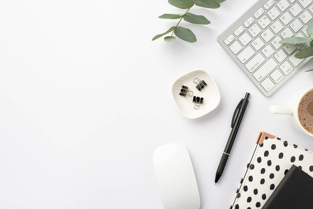 ビジネスコンセプト。職場のキーボードコンピュータマウスの写真黒と白のトレンディーなノートパッドペンバインダークリップコーヒーとユーカリのカップ孤立した白の背景 - 写真・画像