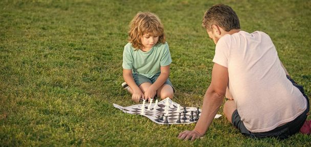 パパと子供はロジックゲームをする。コピースペース。公園でチェスをしてる父親と息子。父の日。家族だ。親と子供の頃。チェックメイト。一緒に時間を過ごす。戦略的戦術。指導法. - 写真・画像