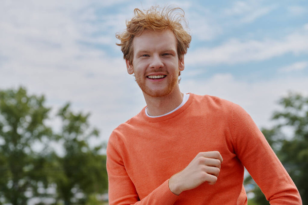 Cheerful young redhead man looking at camera and smiling while standing outdoors - Φωτογραφία, εικόνα