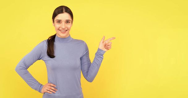 female fashion model point finger. pretty look of young girl. face portrait of lady on yellow background. express positive emotions. advertisement. cheerful woman pointing finger on copy space. - Photo, Image