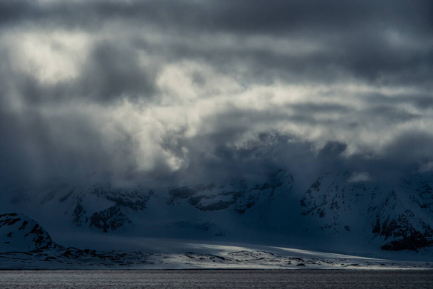 Dramatic mountain landscape in Svalbard. Dramatic clouds over snowy mountains in the arctic. In the foreground the Greenland Sea. High quality photo - Fotó, kép