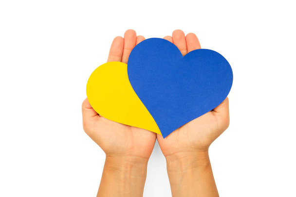 Women's hands hold hearts cut out of paper, painted in the national colors of Ukraine blue and yellow. Ukrainian flag - Foto, Imagen
