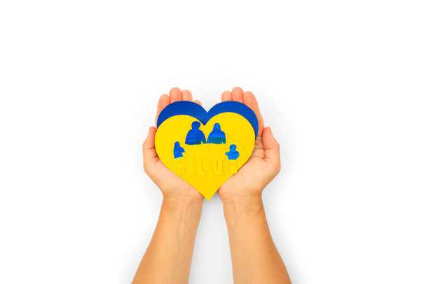 Woman hands hold a paper-cut family painted in the national colors of Ukraine. Ukrainian flag - Фото, зображення