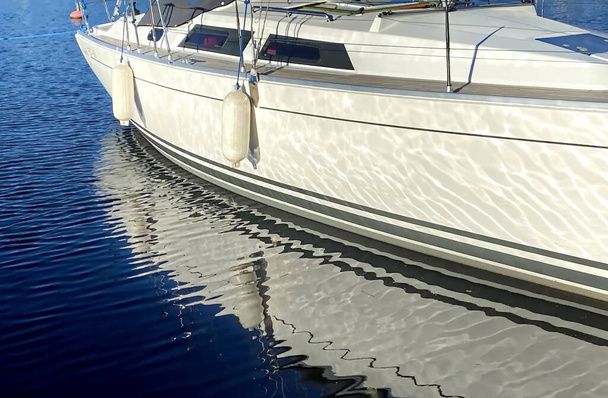 Яхтський човен спереду в гавані відображення на морській воді, фоні пристані та Яхтса
  - Фото, зображення