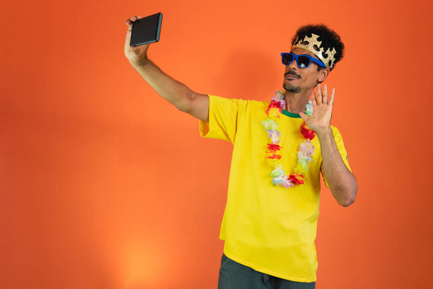 Man in yellow soccer outfit holding mobile Isolated on Orange Background. - Foto, afbeelding