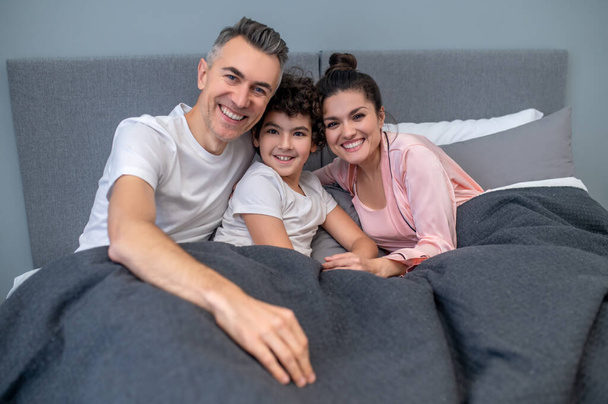 Happy family. A happy family in bed together looking peaceful - Фото, зображення