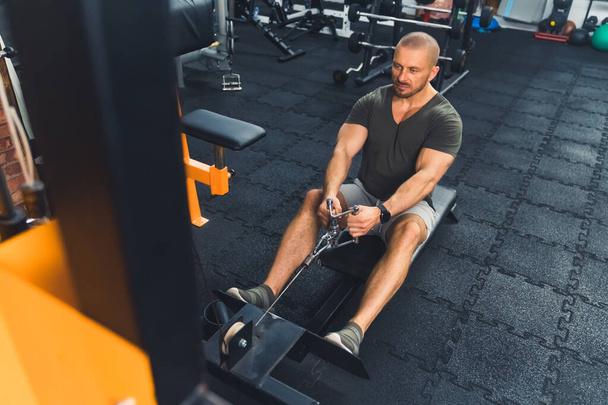Muscular caucasiano homem de meia-idade personal trainer usando máquina de pesos para braços no ginásio. Conceito de estilo de vida saudável. Foto de alta qualidade - Foto, Imagem
