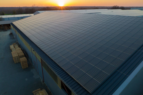 Vista aerea di pannelli solari fotovoltaici blu montati sul tetto di un edificio industriale per produrre elettricità ecologica verde. Produzione di concetto di energia sostenibile. - Foto, immagini