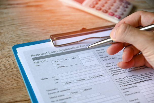 Personal loan concept with loan application form paper with calculator and business manholding a penclient signs loan on the table, Loan business finance economy commercial real estate investments. - Photo, Image