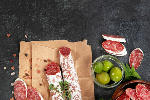 Traditional Spanish fuet on gray background. Dry cured pork sausages with peculiar taste. Flat lay, top view, copy space - Foto, imagen