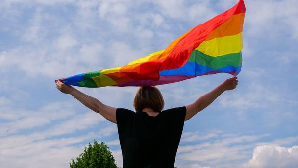 Mese di orgoglio LGBTGIA, bandiera della pace arcobaleno contro il cielo blu con nuvole in una giornata di sole e celebrare la Giornata della Bisessualità o Giornata Nazionale di coming out - Foto, immagini