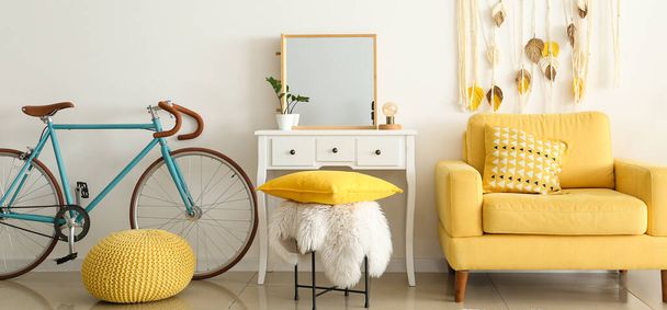 Innenraum des hellen Zimmers mit gelbem Sessel, Frisiertisch und Fahrrad - Foto, Bild