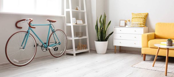 Elegante interior de la habitación con bicicleta, estantes, cómoda y sillón - Foto, Imagen