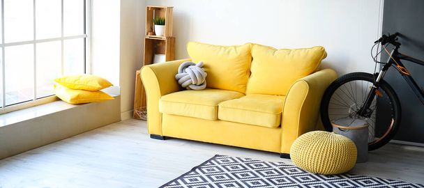 Gelbes Sofa und Fahrrad im Inneren des stilvollen Wohnzimmers - Foto, Bild